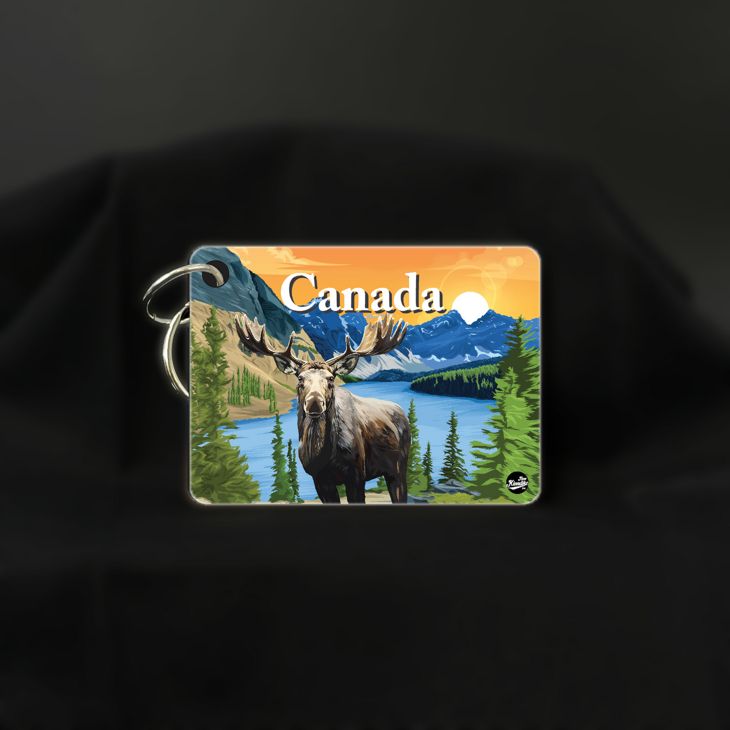 Art key chain featuring a moose silhouette with a sunrise over the Canadian Rockies, by New Klondike Arts and Media.