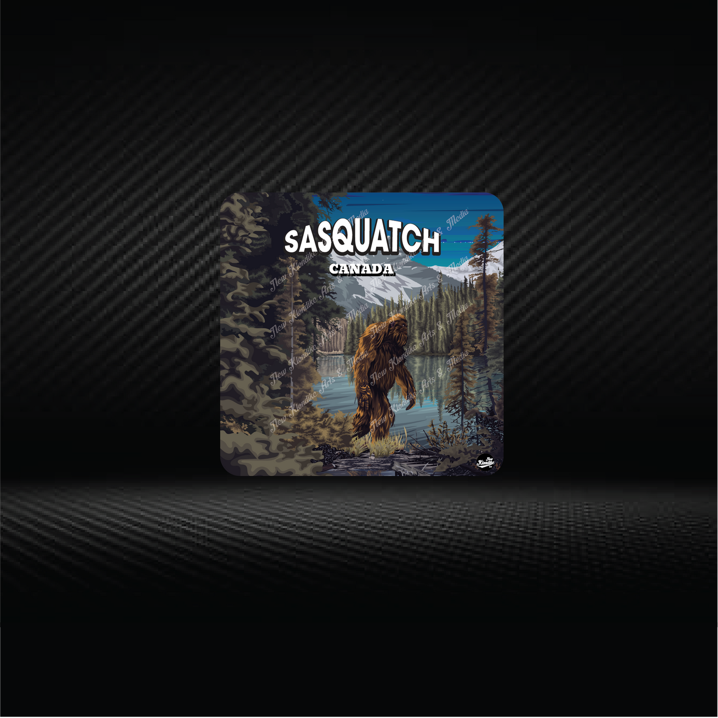 Art coaster featuring Sasquatch by a lake in Canada, from New Klondike Arts and Media, showcasing a scenic wilderness illustration.