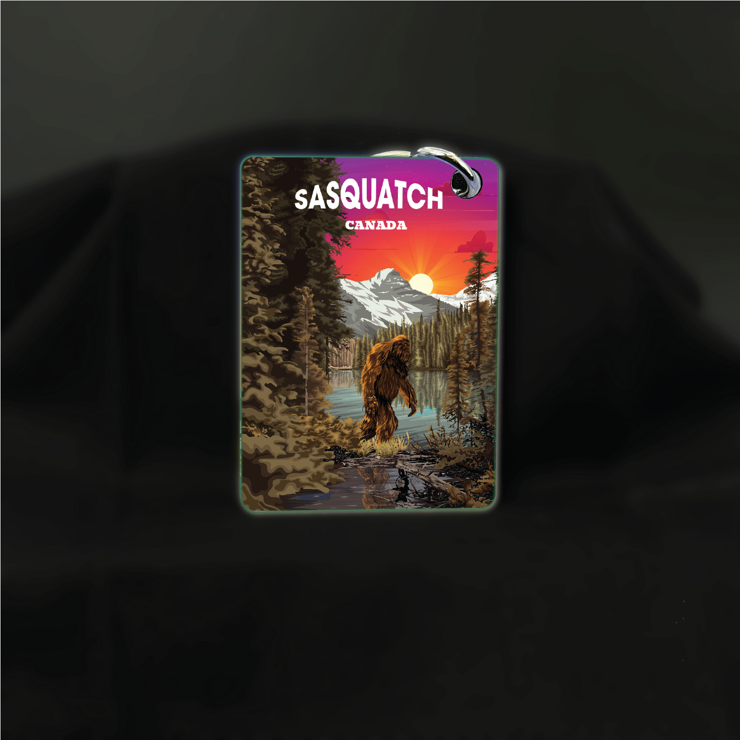 Art key chain featuring a Sasquatch illustration in a lakeside sunrise scene, by New Klondike Arts and Media.