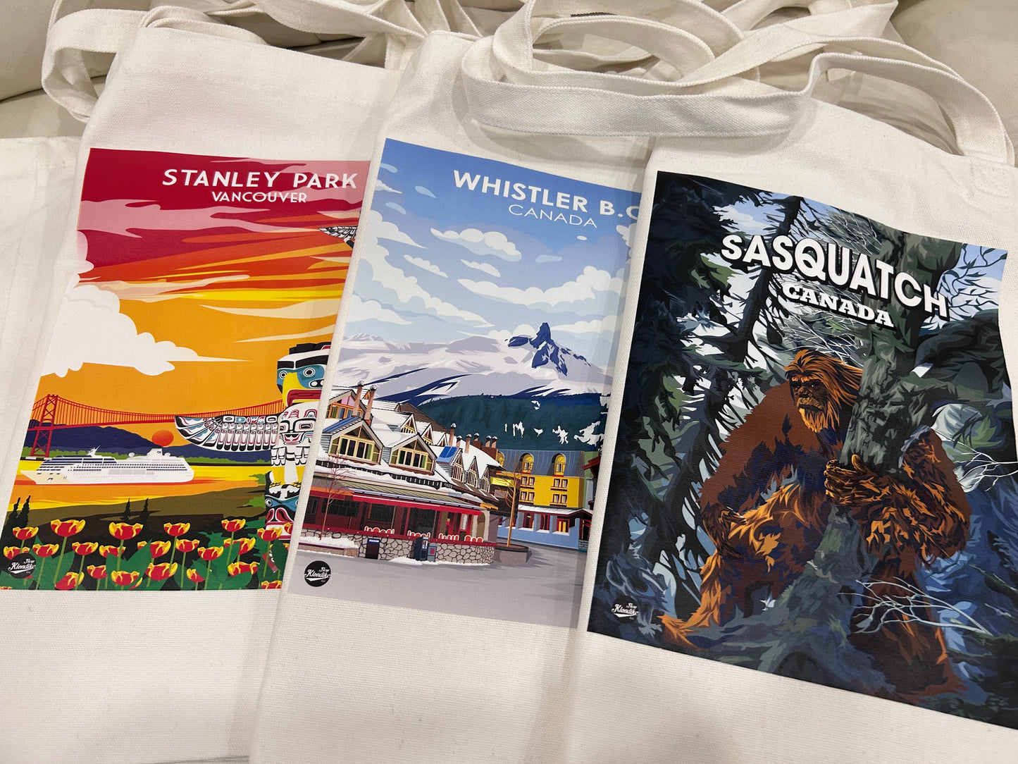 Canvas tote bag featuring a Whistler Canada design by New Klondike Arts and Media, shown with handles and vibrant outdoor scenery.